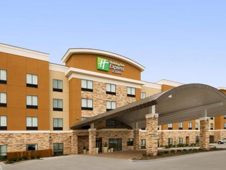 The image shows a Holiday Inn Express & Suites hotel with a large arched entrance and a multi-story building facade.
