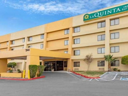 The image shows the exterior of a La Quinta Inn & Suites hotel, featuring a yellow building with a signage and entrance area.